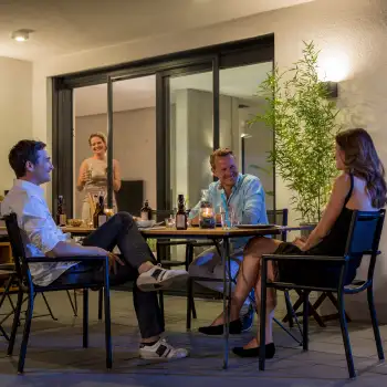 Abendliche Terrassenszene mit geöffneter Fliegengitter Schiebetür und vier Personen