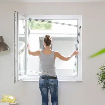 Frau bringt einen Fliegengitter Spannrahmen SP 2/1 in ein geöffnetes Fenster ein