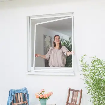 Frau setzt einen Fliegengitter Spannrahmen in ein geöffnetes Fenster ein