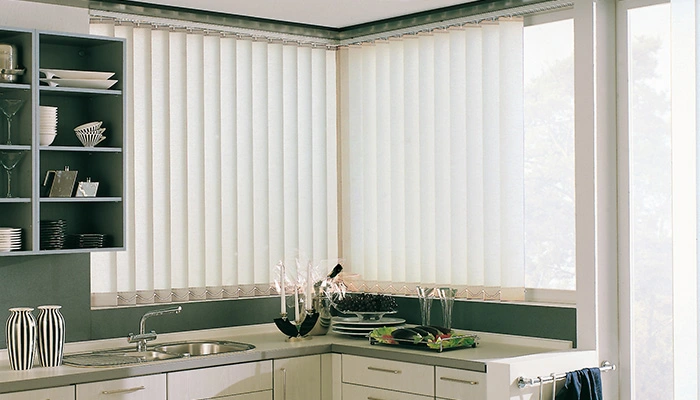Zwei weiße Lamellenvorhänge am Eckfenster in einer Küche